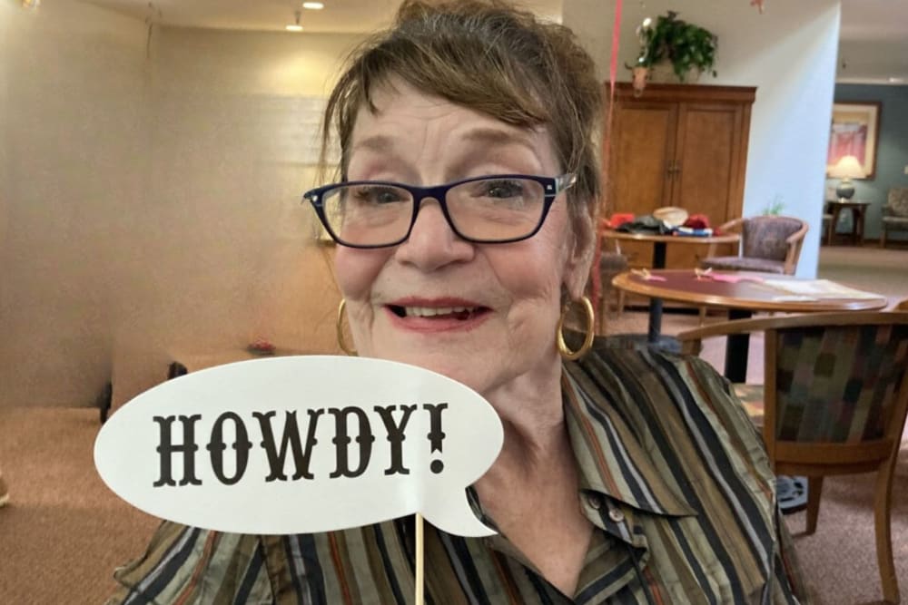 Resident holding a howdy sign at  Hilltop Commons Senior Living in Grass Valley, California