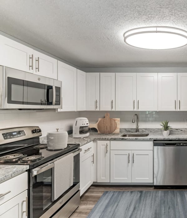 White wooded cabinets in the kitchen with tons of space on counters for cooking and baking at Eagle Rock Apartments at Manchester in Manchester, New Hampshire