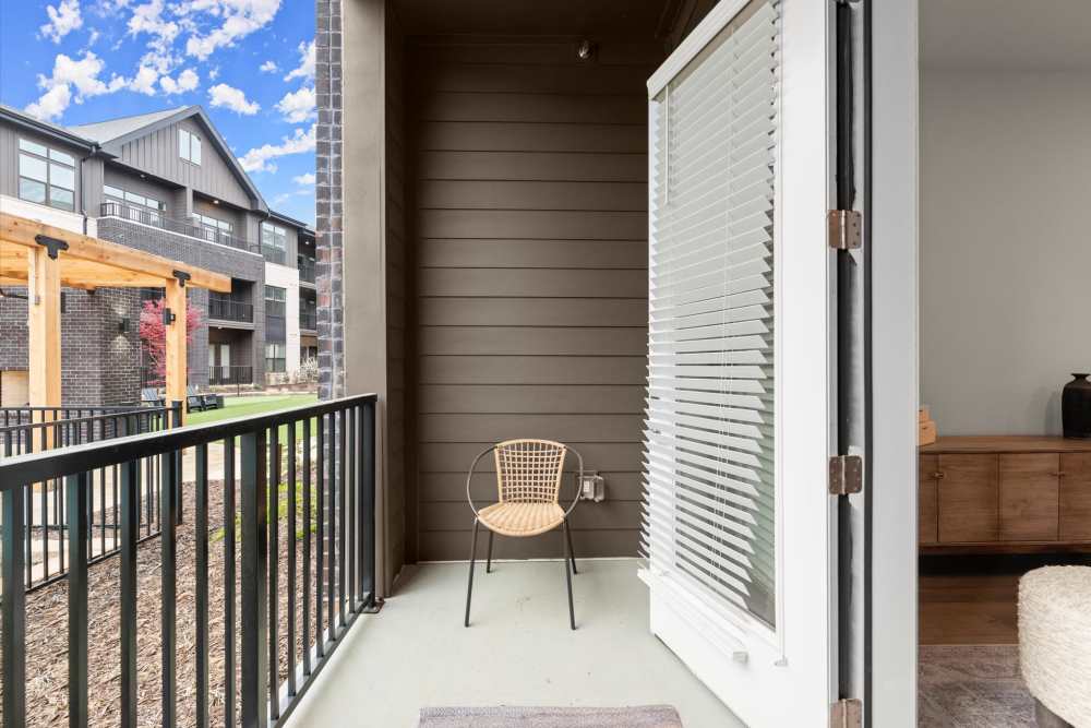 A balcony equipped with a chair and a table, ideal for enjoying fresh air and views at EVOQ East Cobb in Marietta, Georgia