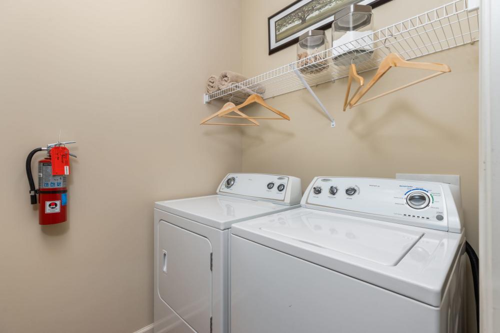 Laundry room with fire extinguisher and full size washer and dryer at Wembly at Overlook in Macon, GA.