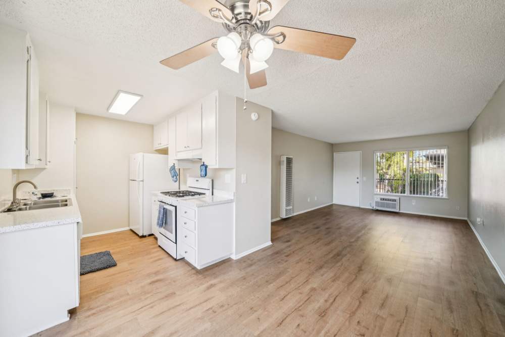 Bright open kitchen and living area with wood‑style flooring and a ceiling fan at Casa Sierra Apartments in Riverside, California