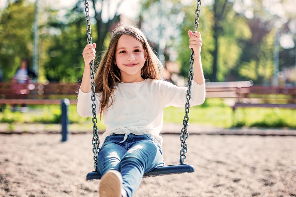 A little girl smiling on a playground swing at Groton Estates in Groton, Connecticut