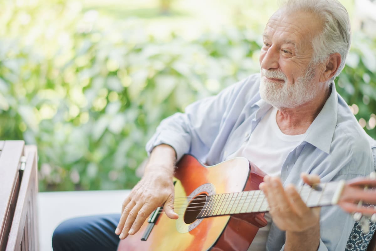 Resident playing the guitar at Oxford Glen Memory Care at Grand Prairie in Grand Prairie, Texas