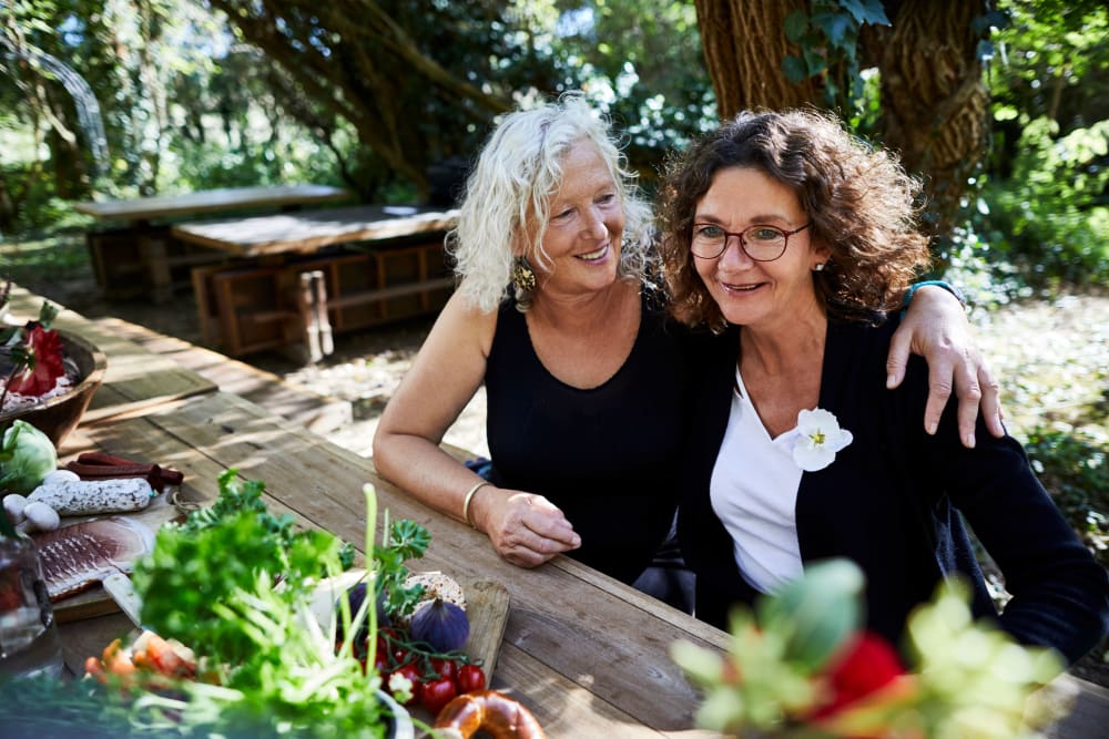 Two women sitting in front of a garden at Concord Place in Concord, North Carolina