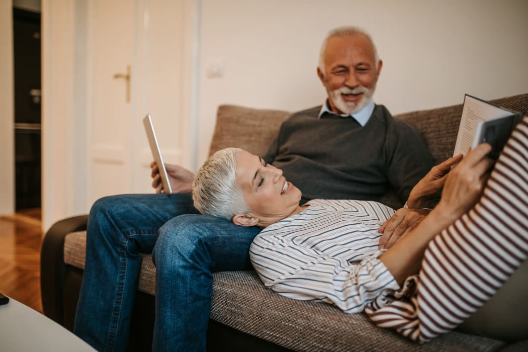 Couple reading on a coach in the living room at Emblem Alpharetta in Alpharetta, Georgia