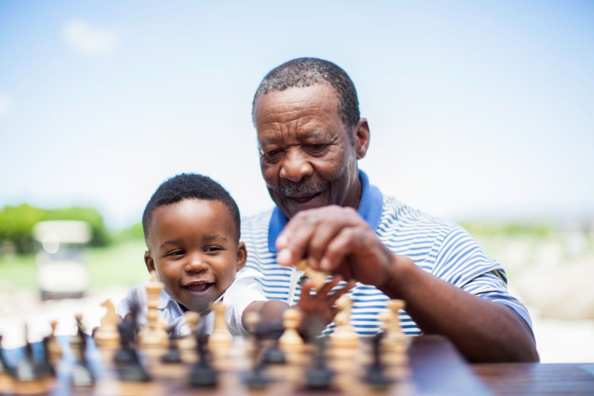 A resident teaching his grandson how to play chess at The Oxford Grand Assisted Living & Memory Care in Kansas City, Missouri