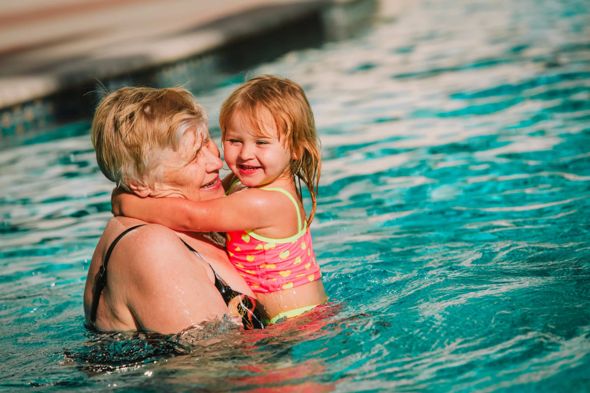 A senior with a young child in the pool at Gables of Ojai in Ojai, California