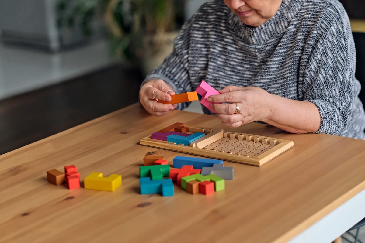 Resident with puzzle blocks at Trustwell Living at Hunters Crossing Place in Gainesville, Florida