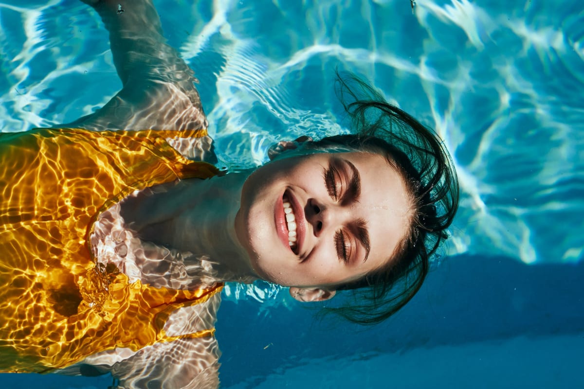 A smiling woman floating in the community pool at Artisan Living North Beach in Santa Rosa Beach, Florida