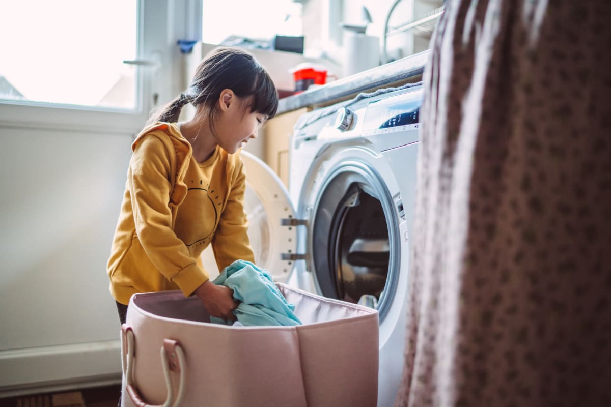 Woman putting laundry in the washer at Via Holon Apartments in Greenbrae, California