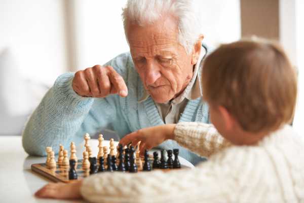 Resident playing chess with a kid at The Pineapple House at Sapphire Lakes in Naples, Florida