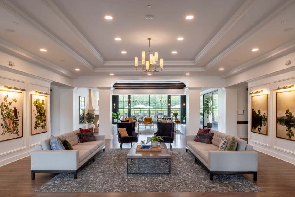 Lounge with a chandelier hanging above a coffee table, which is encircled by tables and chairs at an Amira community