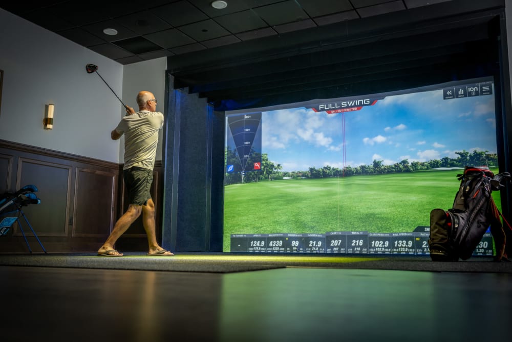 Person playing golf with a golf simulator at an Amira community