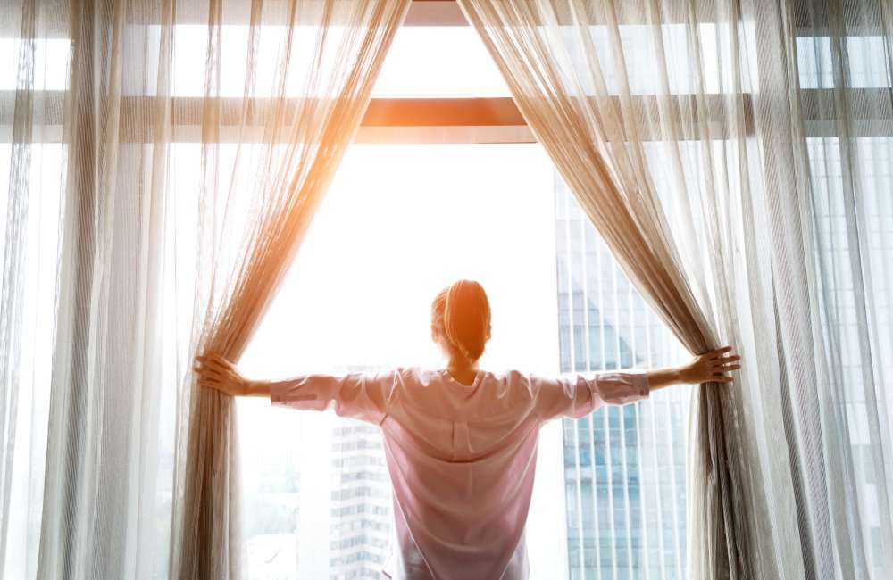 Woman standing in front of an oversized window, peering outside at Copper River in Spokane, Washington