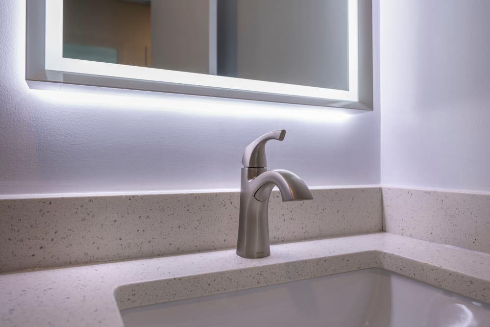 Bathroom sink with quartz countertop and backlit mirror at Ruxton Towers Apartments in Towson, Maryland