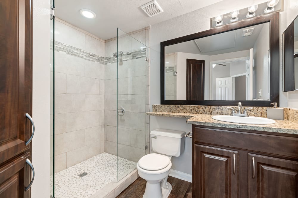 Bright bathroom with granite counter and full size bathtub at Marquis at Stonegate in Fort Worth, Texas