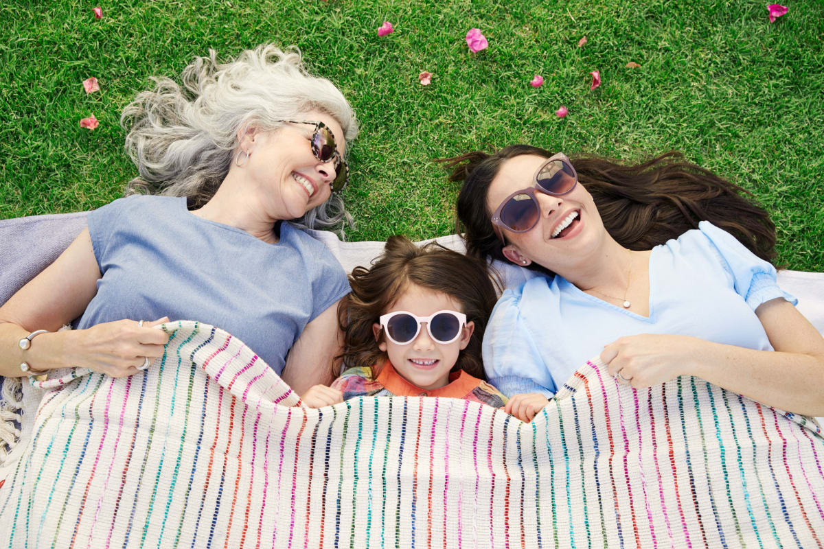 Three residents lying on a blanket in the grass at BB Living at Union Park in Phoenix, Arizona