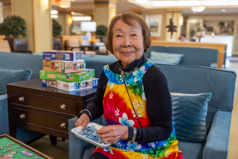 Resident smiling while putting a puzzle together.