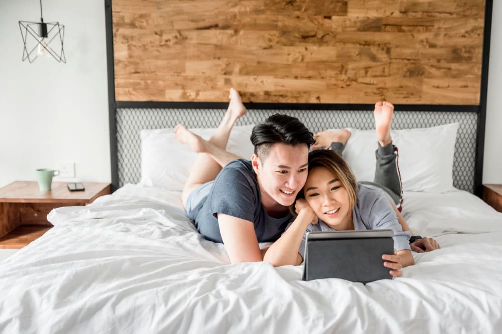 Couple looking at a tablet in bed at Derby in Phoenix, Arizona