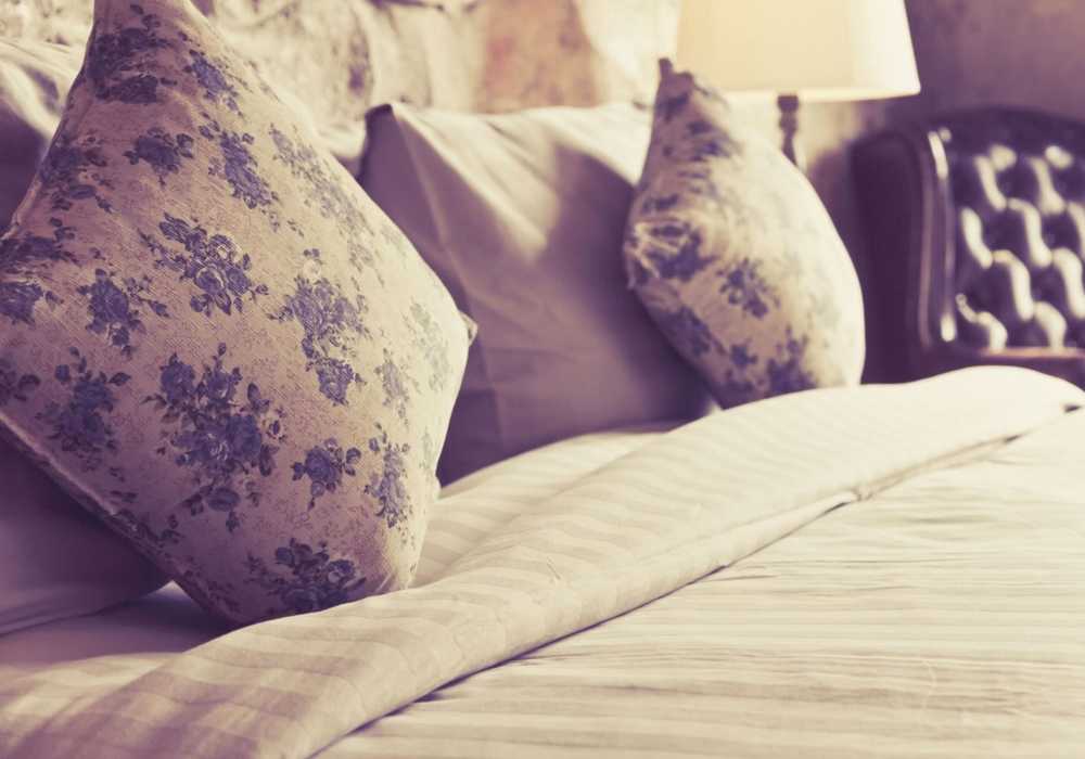 Cozy bedroom with decorative pillows at Windsor Gardens Apartments in Rochester, New York