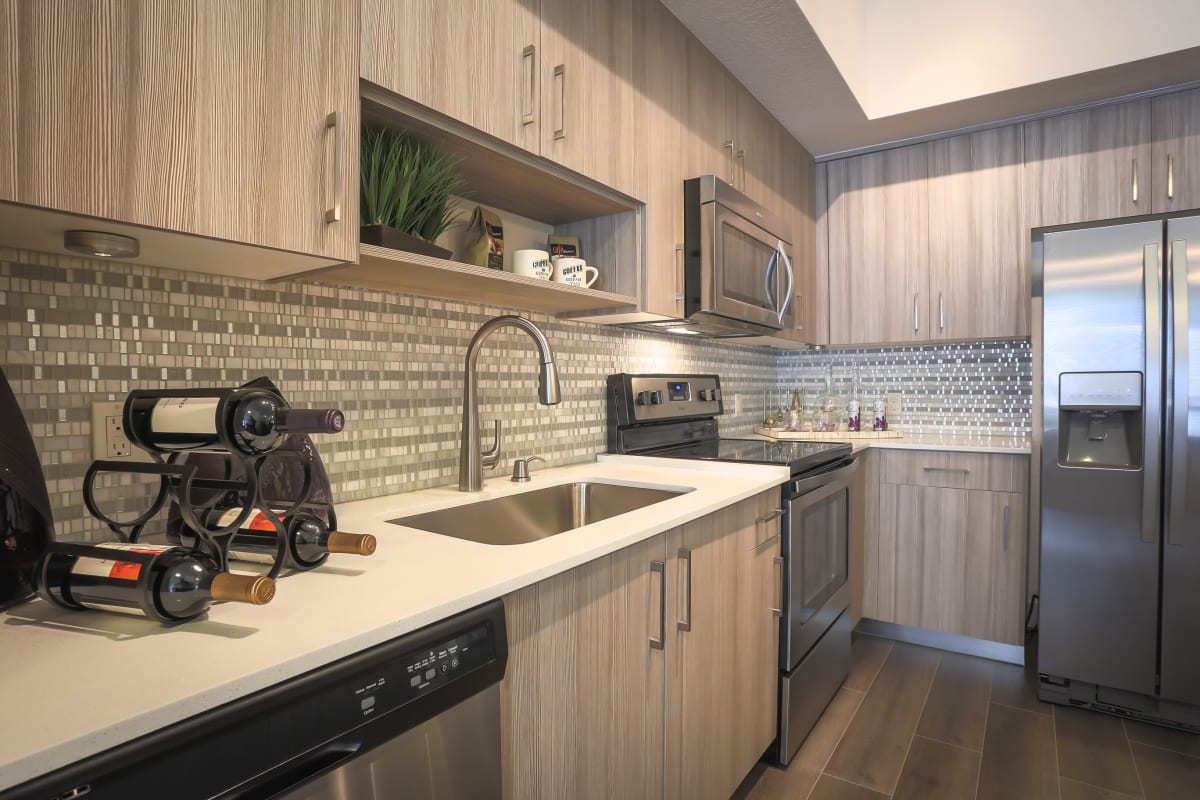 Gorgeous gourmet kitchen with stainless-steel appliances and antiquing treatment on the cabinetry in a model home at Loftin Place Apartments in West Palm Beach, Florida