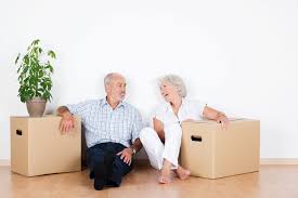 Elderly couple sitting in their home with moving boxes. 