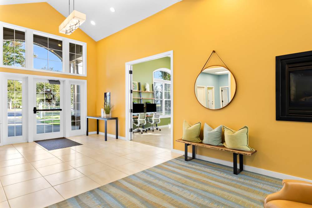 Lobby With a Bright Yellow Wall And a Round Mirror at Arbor Brook in Murfreesboro, Tennessee