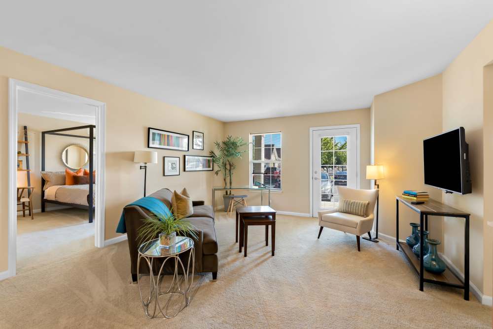 Living Room with Brown Sofa, Glass-topped Coffee Table and a Mounted Flat Screen TV at Arbor Brook in Murfreesboro, Tennessee