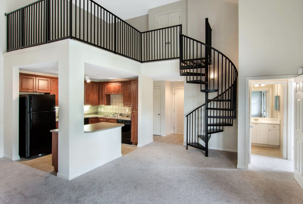 Open-concept floor plan with hardwood floors and accent wall in the living area of model home at Cavalier @ 100 in Lithonia, Georgia