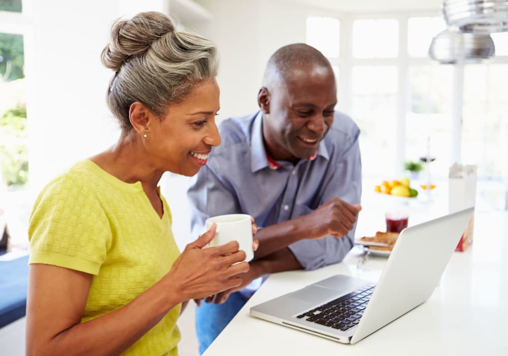 Couple checking out the latest events around Salisbury, Maryland on a laptop in their bright kitchen at Cottages at Riverhouse