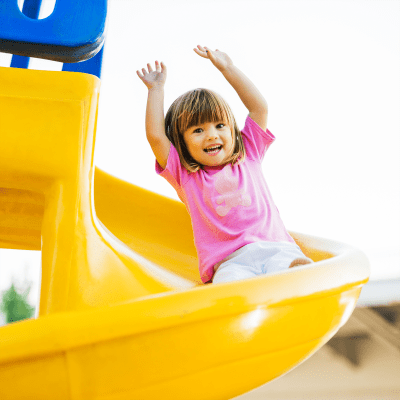 Resident kid sliding down a big yellow slide on the playground at BB Living in Scottsdale, Arizona