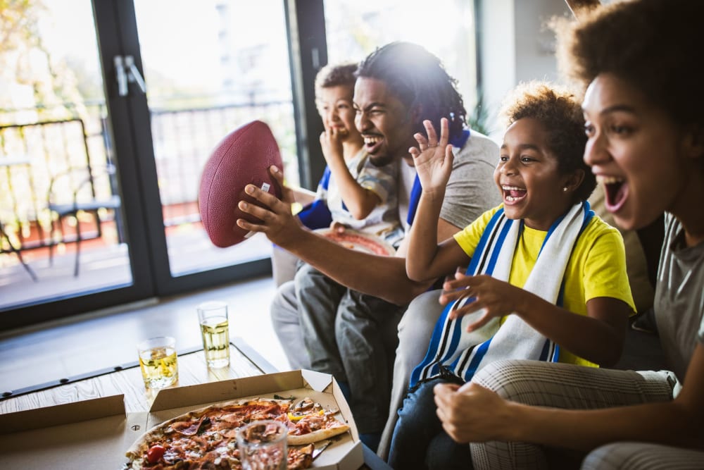 Family watching football and eating pizza in their home at The Eleven Hundred in Sacramento, California