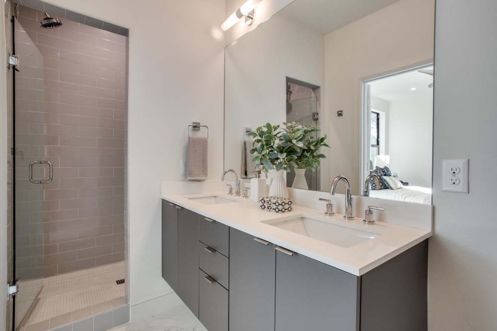 Apartment bathroom with double sink and large mirror at The Collection Townhomes in Dallas, Texas