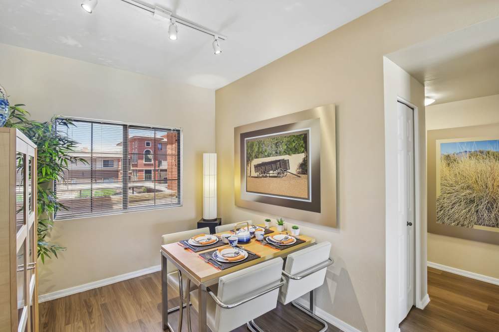 Dining area with small table, wall art, and natural light from adjacent window at Oro Vista Apartments in Oro Valley, Arizona