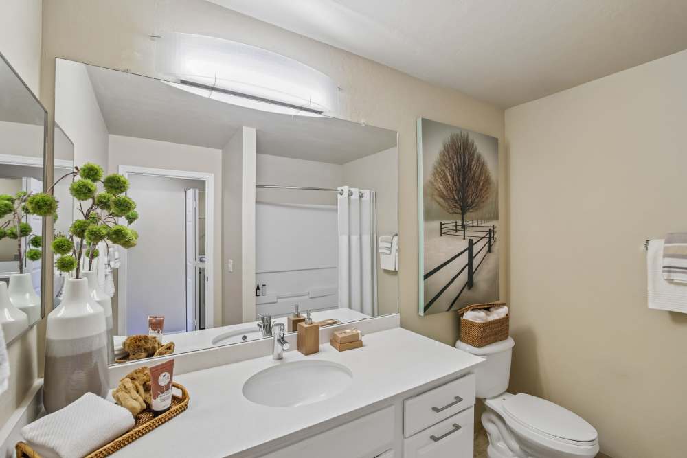 Bathroom with dual vanity mirrors, white countertops, and neutral tile flooring at Oro Vista Apartments in Oro Valley, Arizona