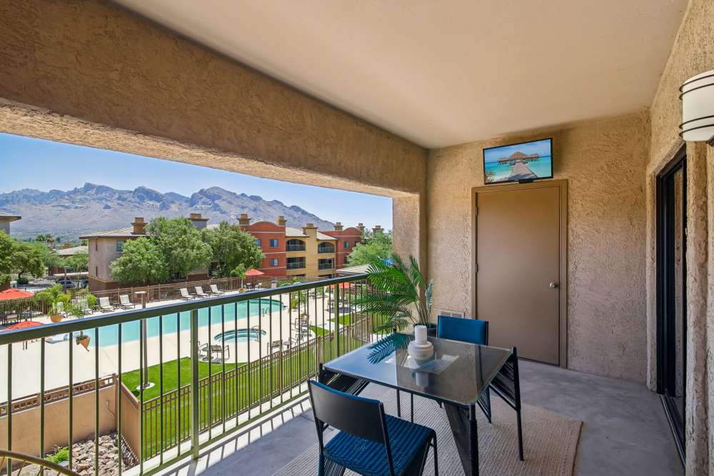 Covered balcony overlooking swimming pool and mountain view, with outdoor seating at Oro Vista Apartments in Oro Valley, Arizona