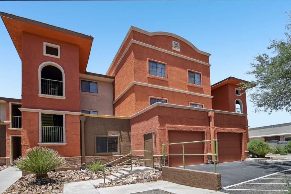 Exterior view of a multi-story Southwestern-style apartment building with terracotta and beige stucco facade at Oro Vista Apartments in Oro Valley, Arizona