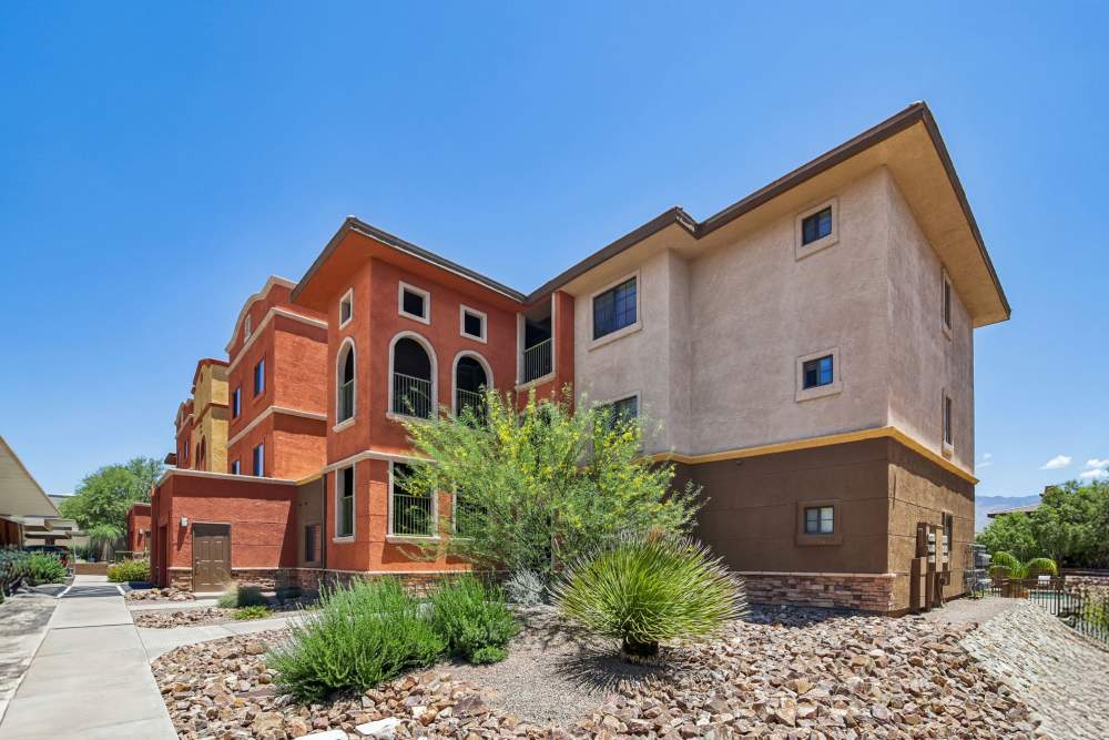 Apartment building exterior with desert landscaping and covered parking area at Oro Vista Apartments in Oro Valley, Arizona