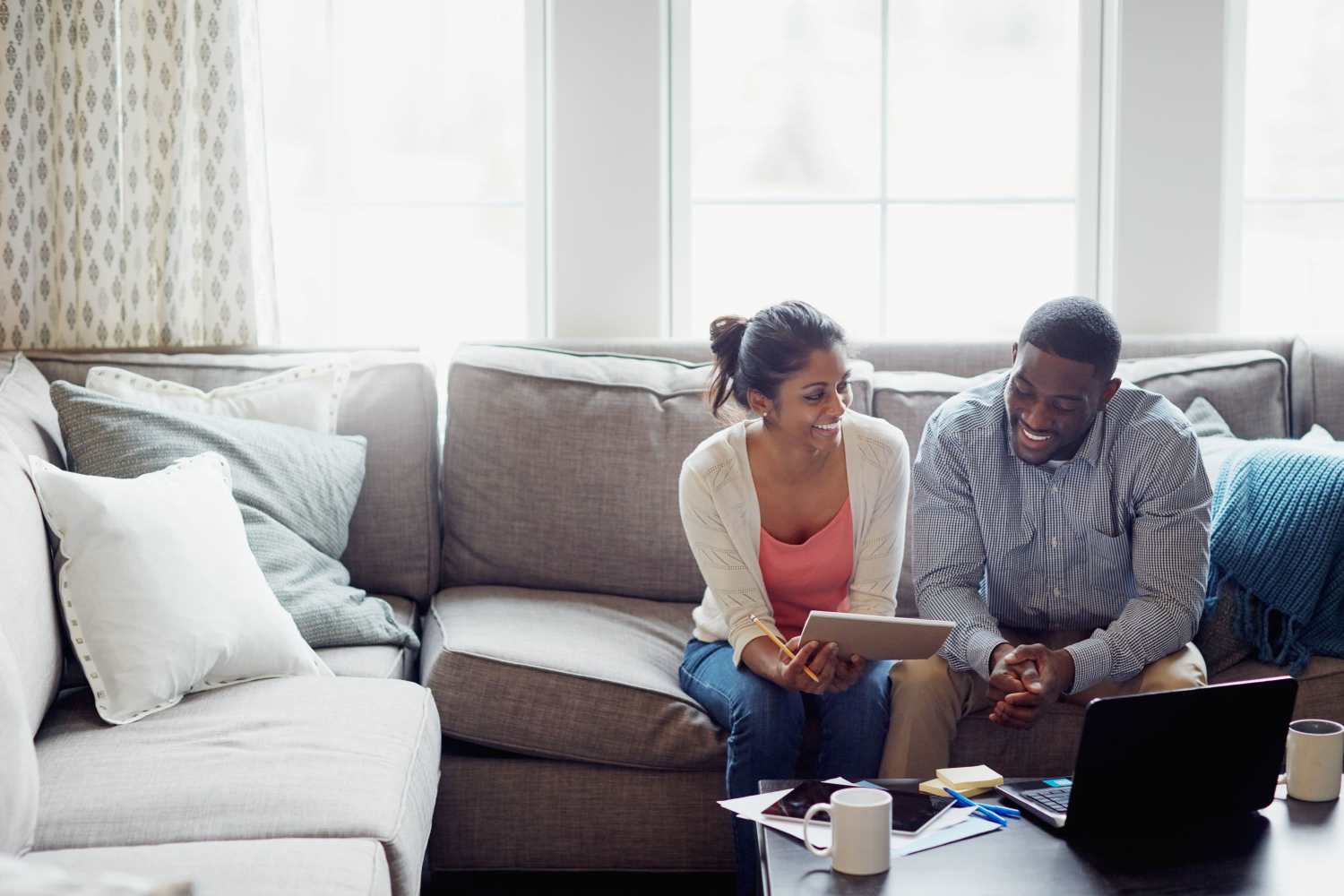 A couple sitting on the couch and talking in their living room at Old Hundred Trace Apartments in Midlothian, Virginia