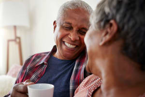 A smiling couple sitting on their sofa at Mariposa at River Bend in Georgetown, Texas