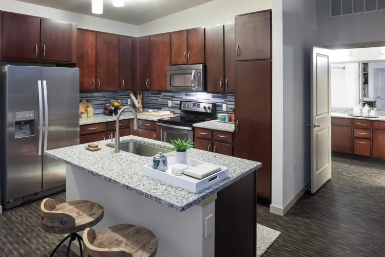 Gourmet kitchen with granite countertops and dark wood cabinetry in a model home at Regatta Sloan's Lake in Denver, Colorado