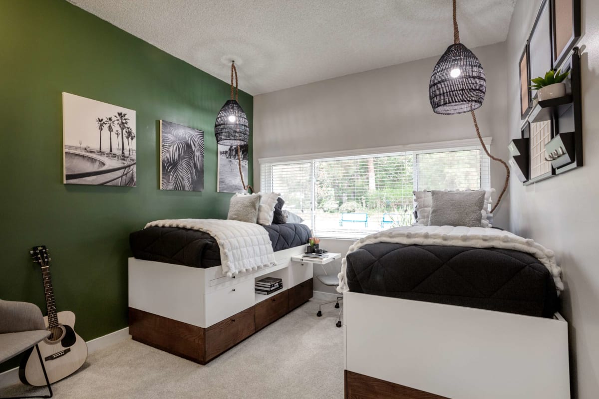 Open living space with two single beds and carpeting at Axiom Westwood in Los Angeles, California
