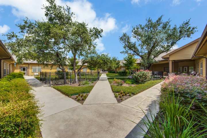 Beautiful courtyard at The Landing at Stone Oak, featuring peaceful walking paths, lush greenery, and secure outdoor spaces designed for memory care residents.