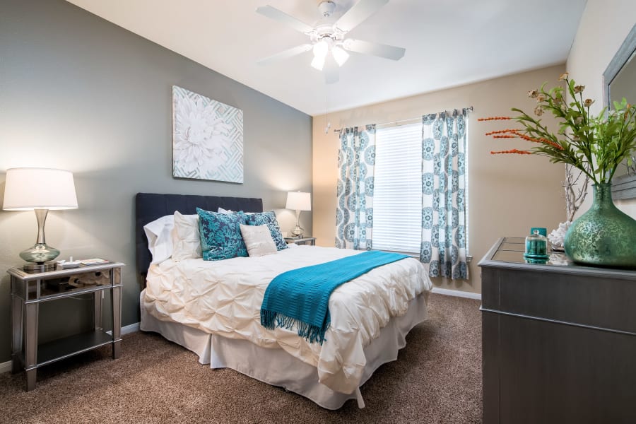 Well-furnished master bedroom with an accent wall and a ceiling fan in a model home at Reserve at Pebble Creek in Plano, Texas