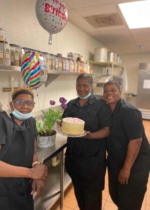 three women one holding a cake at English Meadows Kathwood Campus in Columbia, South Carolina