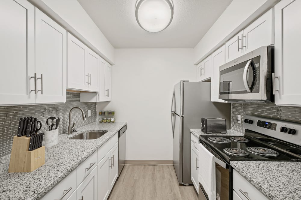 Renovated kitchen with white cabinets, stainless appliances, granite counters, and vinyl plank floors
