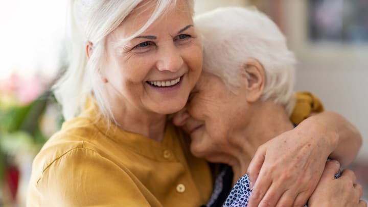 Two senior women smiling and hugging