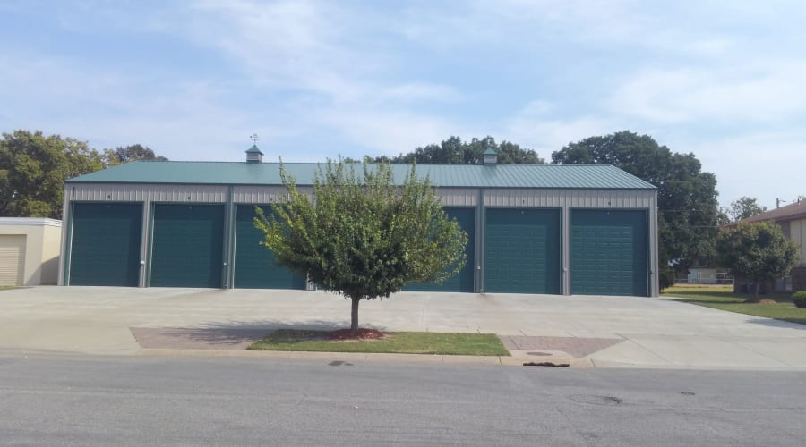 A tree in front of green storage units at KO Storage in Salina, Kansas