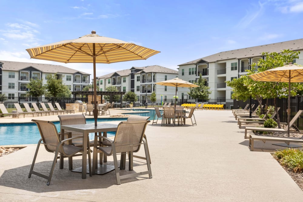 Pool side area with tables and chairs at Olympus Woodbridge in Sachse, Texas