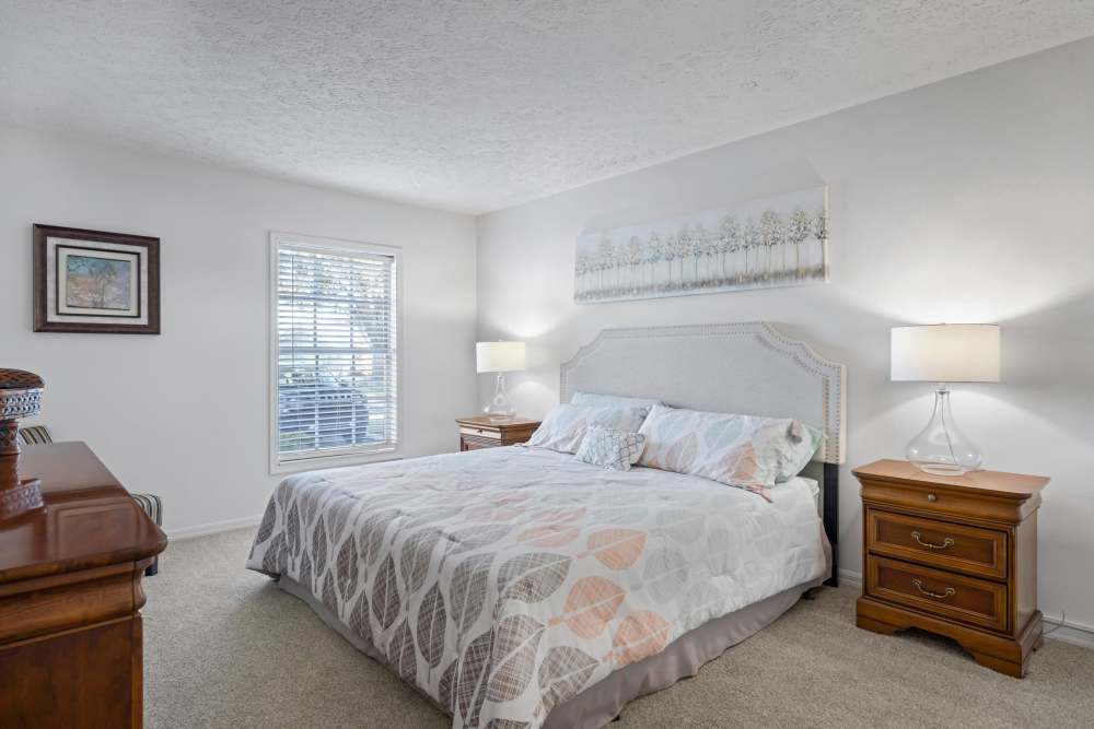 Bedroom with large bed, side table lamps and carpet flooring at Carlton Arms Of South Lakeland in Lakeland, Florida